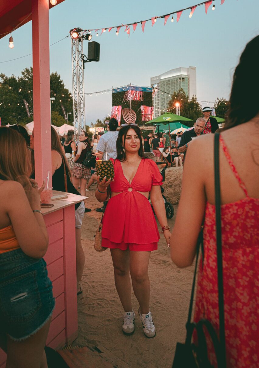 Festivalière avec un cocktail dans un ananas sur la plage éphémère du Festival Parasol