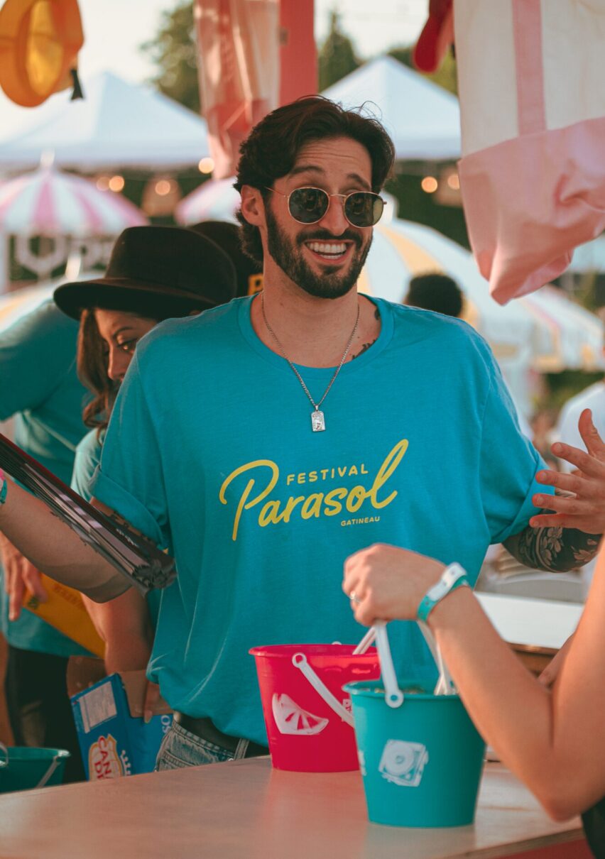 Un bénévole souriant portant le chandail du festival 