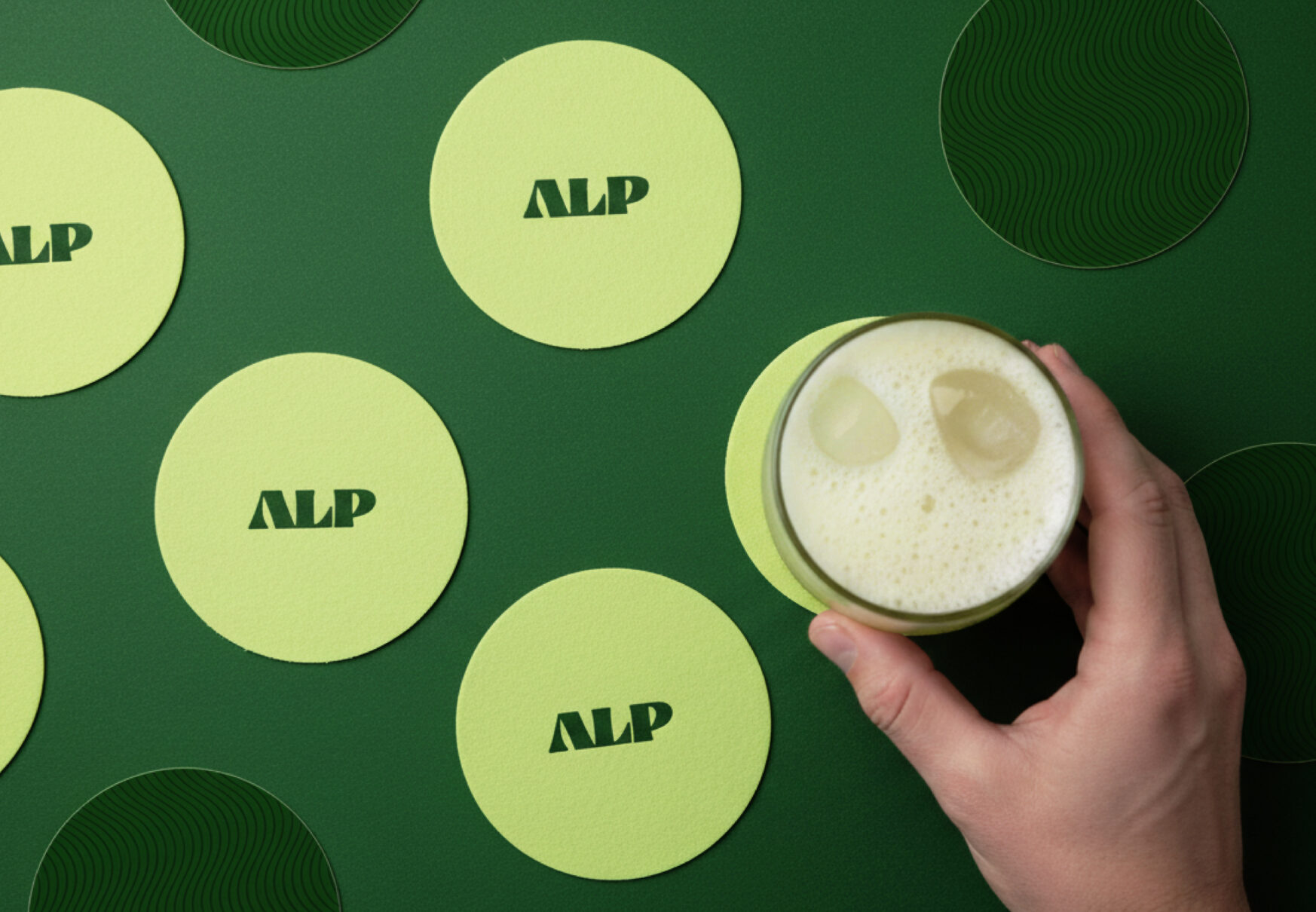Sous-verres promotionnels verts avec logo ALP et main tenant un verre, identité visuelle conçue par Orkestra